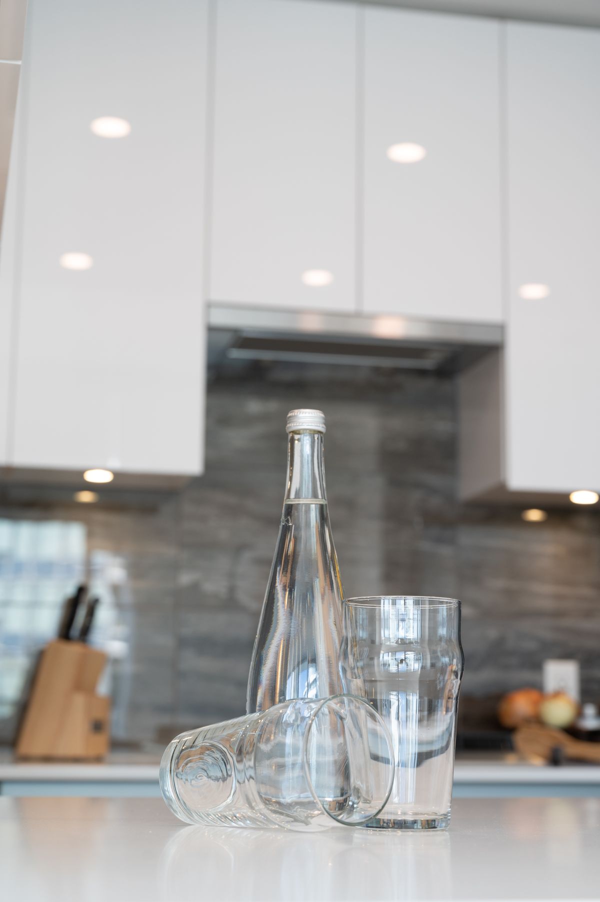 Clean, bottled-quality water in glasses on a modern kitchen counter — the everyday result of a whole-home water treatment system